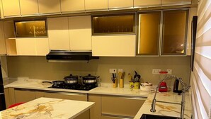 Een moderne keuken met een marmeren aanrecht, een fornuis, een spoelbak en een raam met jaloezieën.