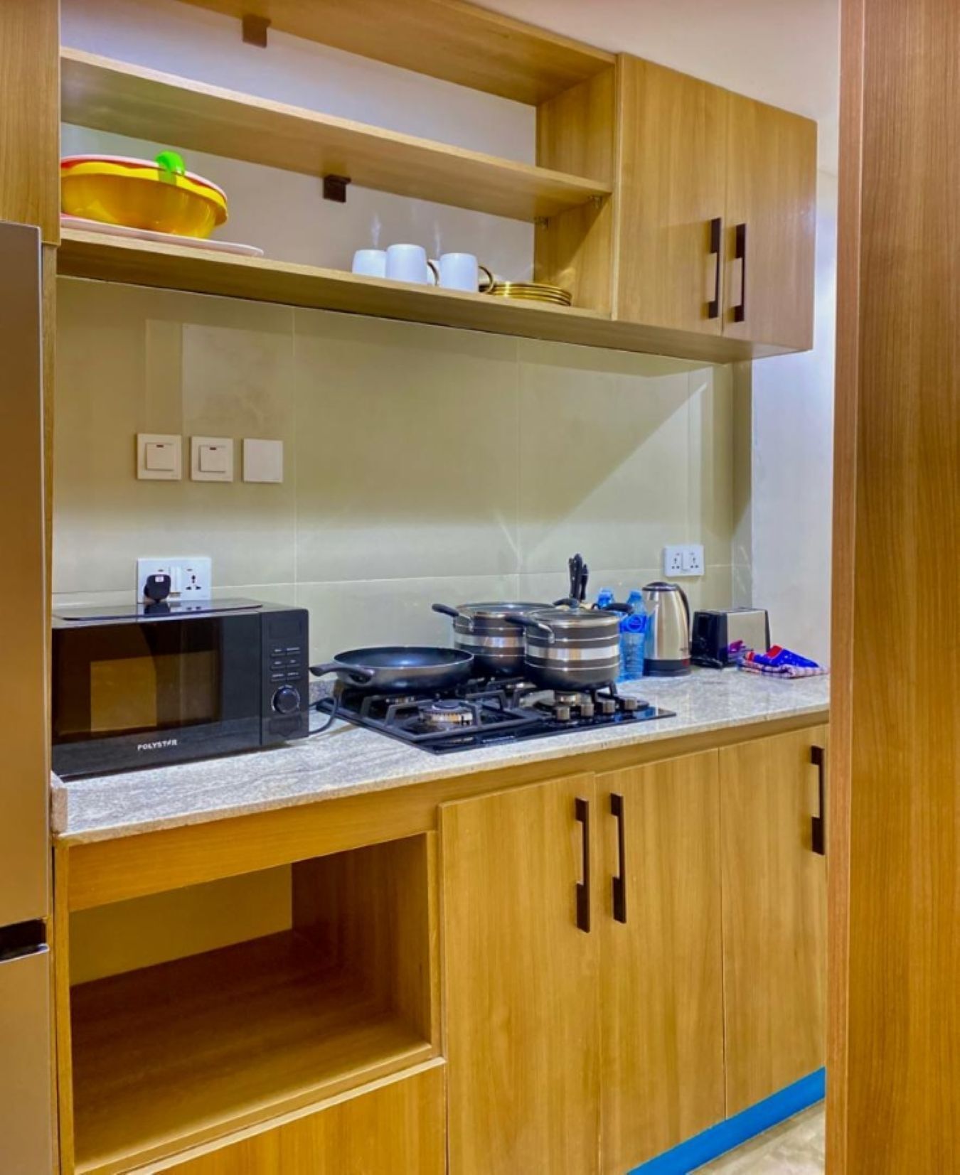 A compact kitchen with a microwave, stove, and various utensils.
