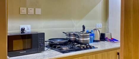 A compact kitchen with a microwave, stove, and various utensils.