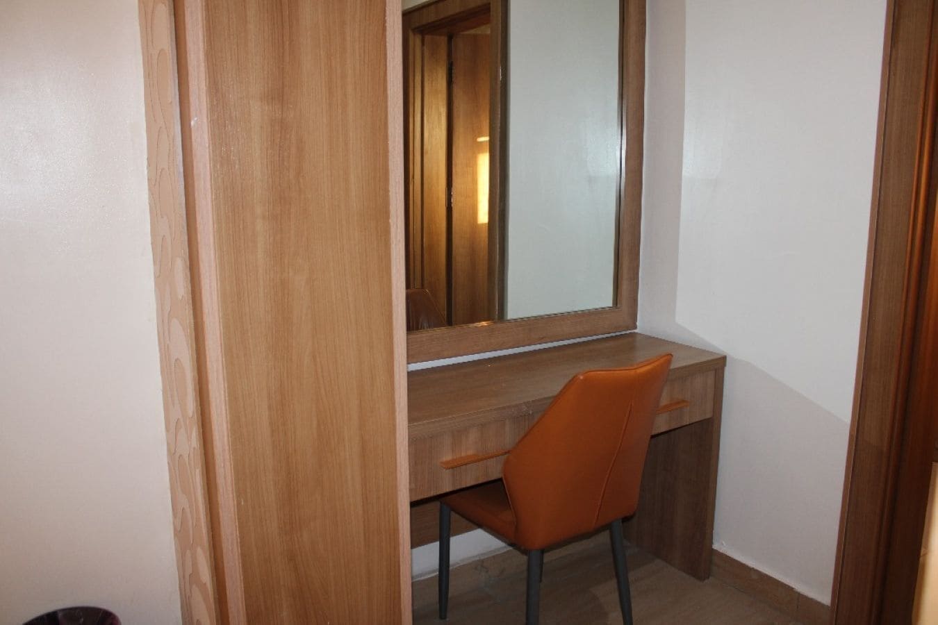 A wooden desk with a chair and a large mirror.