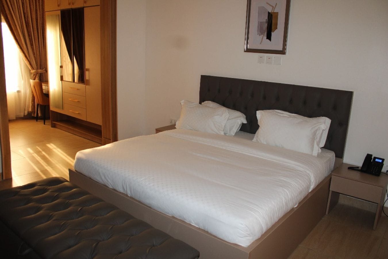 Une chambre d’hôtel comprenant un lit, une table de chevet avec un téléphone, une armoire et une chaise.