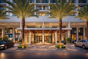 A hotel entrance with a modern facade, palm trees, and a well-lit entrance. - RS Suites - Miami World Center (Miami)