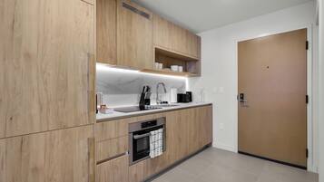 A modern kitchen with wooden cabinets, a built-in oven, a sink, and a countertop with various appliances.