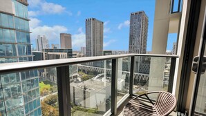A balcony with a chair, overlooking a cityscape with tall buildings and a clear sky. - RS Suites - Miami World Center (Miami)