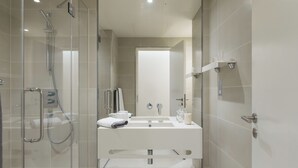 Un bagno moderno con doccia vetro, lavandino bianco e specchio.
