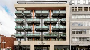 Un edificio a più piani con balconi, un cartello con su scritto "The Quarters Swiss Cottage" e un ingresso ben visibile.