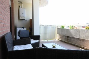 A balcony with wicker furniture, a washing machine, and a water heater. - P088 - Porto Recanati, new three-room apartment with balcony (Porto Recanati)