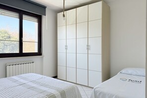 A bedroom with a bed, a wardrobe, a radiator, and a window. - P088 - Porto Recanati, new three-room apartment with balcony (Porto Recanati)