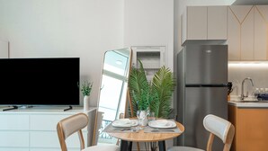 Une cuisine moderne équipée d’un four encastré, d’un réfrigérateur et d’un coin repas avec une table dressée pour deux personnes.