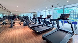 Une salle de sport équipée de tapis de course, de vélos d’exercice et d’appareils de musculation.