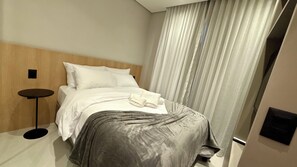 A hotel room with a bed, a round side table, and a large window with curtains. - Modern Studio Alphaville (Barueri)
