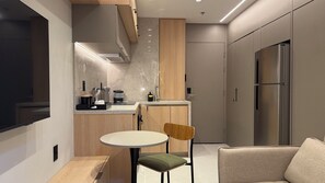 A modern kitchen with a built-in oven, a sink, and a dining area with a table and chairs. - Modern Studio Alphaville (Barueri)