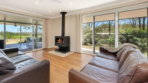 Un salon moderne doté d’une cheminée, de canapés en cuir et de grandes fenêtres offrant une vue sur l’extérieur.