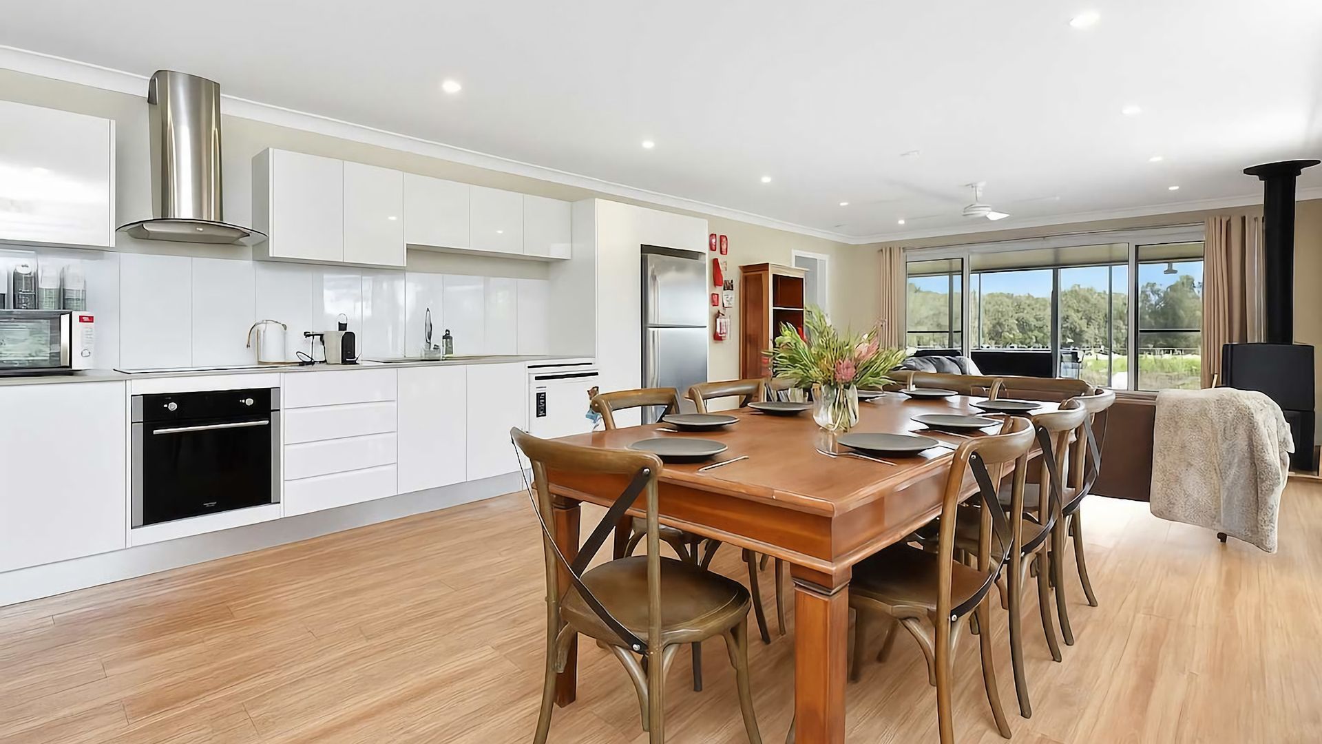 A modern kitchen with white cabinetry, a built-in oven, and a stainless steel range hood.