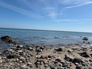 Ein felsiger Strand mit klarem, blauem Wasser und ruhiger See.