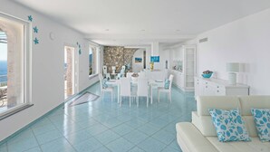 Ein helles Wohnzimmer mit Essbereich, einer Küche und Blick aufs Meer.