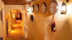 Un couloir doté d’un plafond en bois, de murs en pierre et de plusieurs horloges.