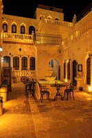Un patio con una fuente, zona de estar y un edificio con ventanas y balcones de arco.
