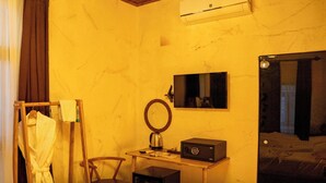Une chambre d’hôtel avec un lit, une table de chevet avec une bouilloire, un miroir et une chaise en bois.