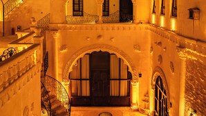 Une cour intérieure avec un escalier, des portes en arc de cercle et un balcon agrémenté de balustrades.