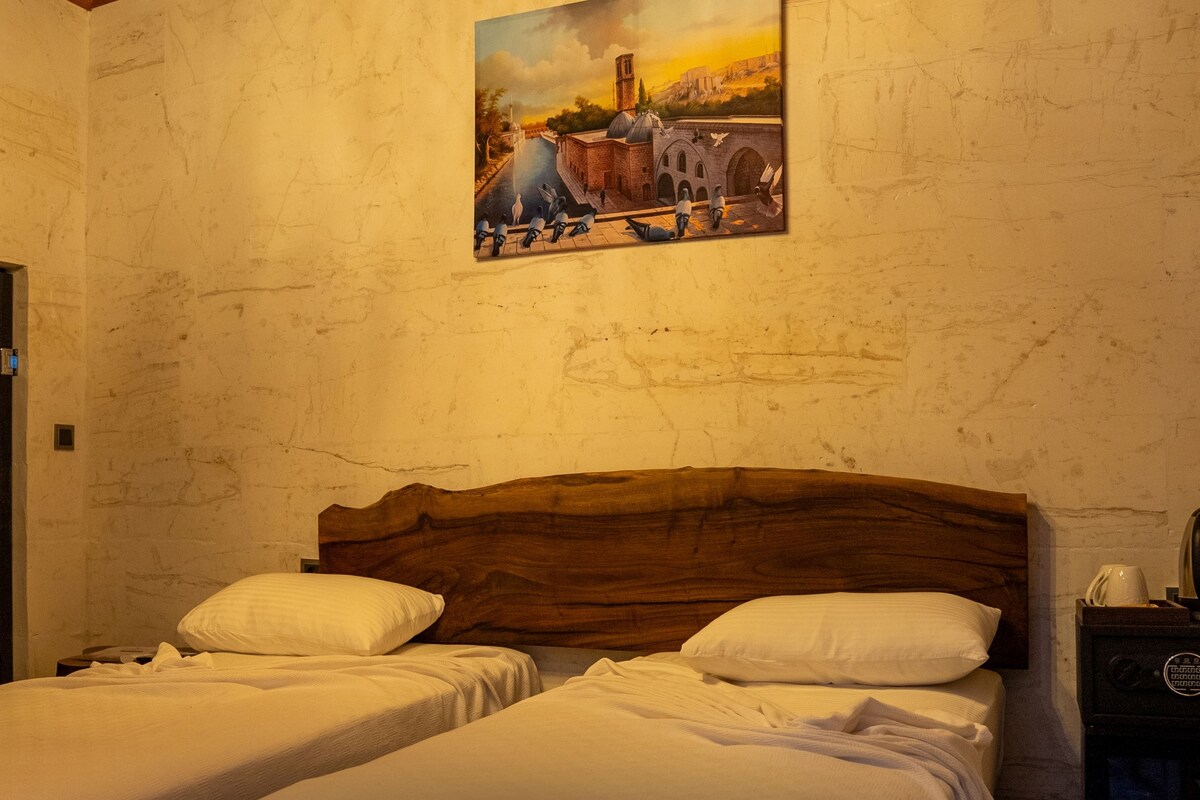 A room with two beds, a painting on the wall, a television, and a coffee machine.