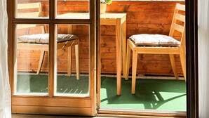 En trærammet skydedør, der fører til et udendørs siddeområde med udsigt over en skov.