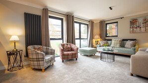 Een woonkamer met een bank, fauteuil, poef en salontafel.
