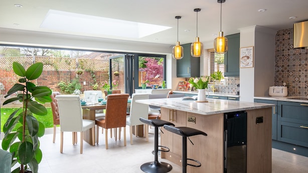 Een moderne keuken met een groot kookeiland, hanglampen en uitzicht op de achtertuin.