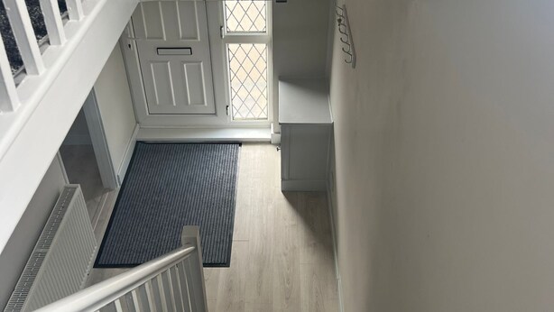 A staircase with a handrail, a landing with a mat, and a door with a window. - Modern Comfort Home | Relax & Unwind in our 4 bed family friendly. (Oxford)