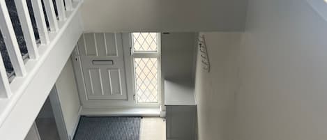 A staircase with a handrail, a landing with a mat, and a door with a window.