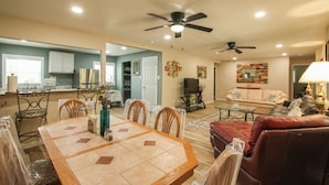 Amplia sala de estar con mesa de comedor, sillas, sofá y televisor.