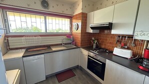 Uma cozinha compacta com janela, pia, fogão e máquina de lavar louça.