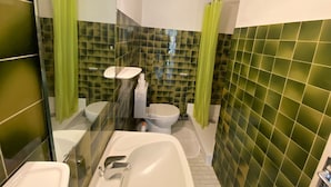 Ein Badezimmer mit Glastrennwand, Waschbecken in Weiß, Toilette und Badewanne.