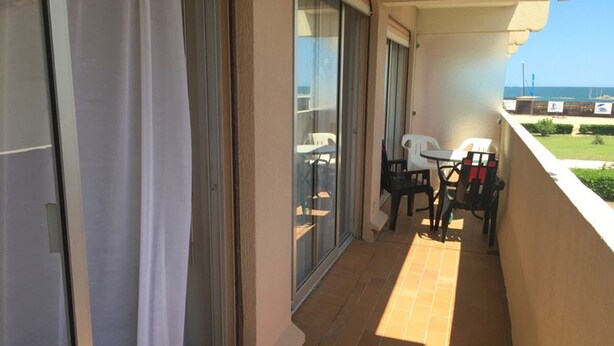 Ein Balkon mit Meerblick, eine Schiebeglastür und ein Tisch mit Stühlen.