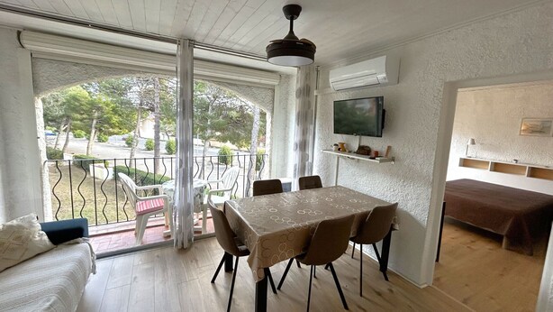 A dining area with a table and chairs, a TV mounted on the wall, and a balcony with a railing. - Apartment near beach - 4 guests (Argelès-sur-Mer)