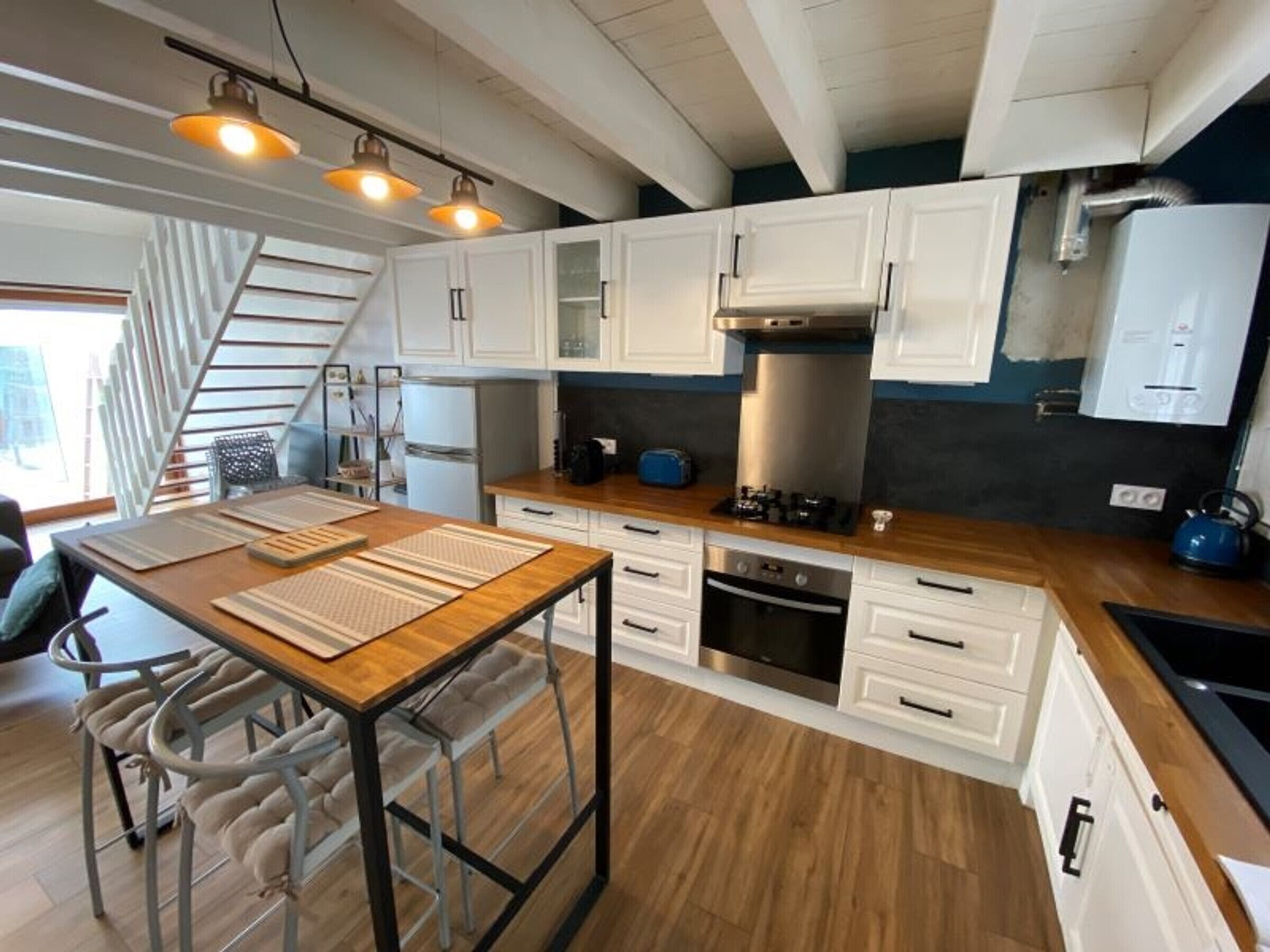 A modern kitchen with white cabinets, a wooden countertop, a built-in oven, and a gas stove.