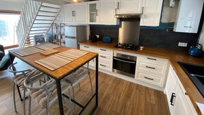 Una cocina moderna con armarios blancos, encimera de madera, horno empotrado y estufa a gas.