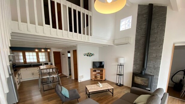 Amplia sala de estar con techos altos, chimenea y balcón.