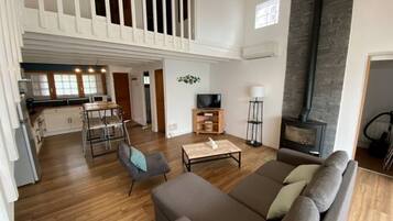 A spacious living area with a high ceiling, a fireplace, and a balcony.