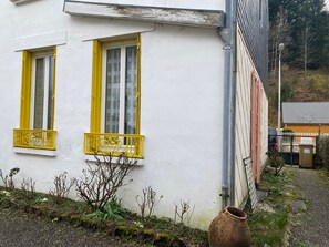 A white building with two windows, each with yellow shutters and a small balcony. - Cozy city-center apartment - 4 guests (La Bourboule)