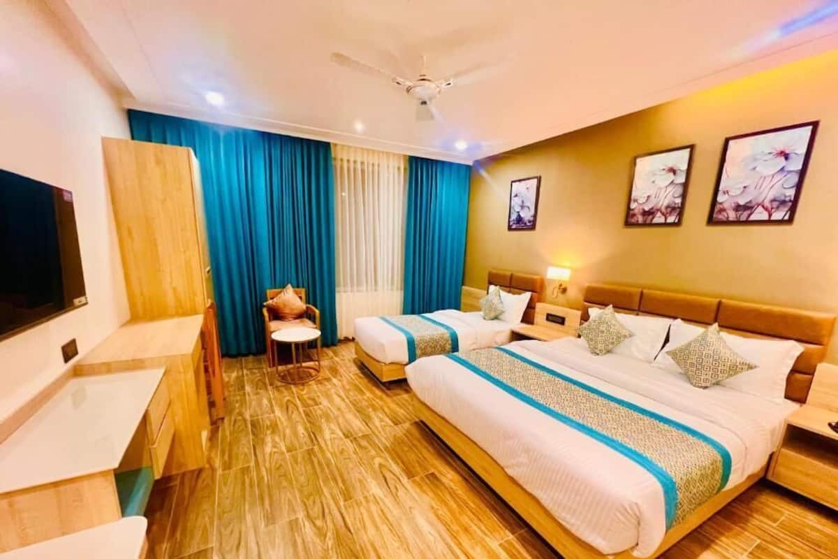 A hotel room with two beds, a TV, a desk, and a chair.