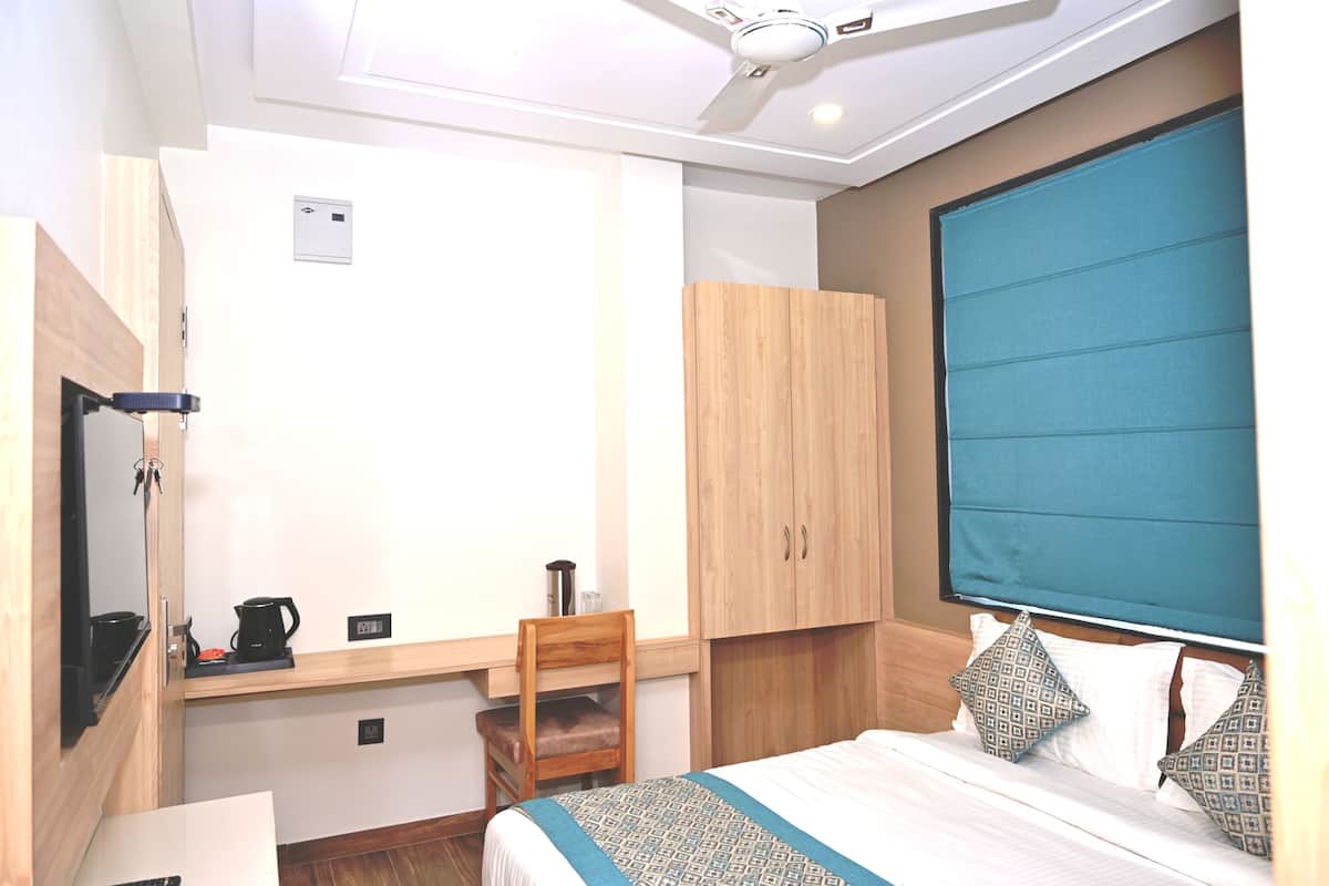 A bedroom with a bed, a desk with a chair, a wardrobe, and a ceiling fan.