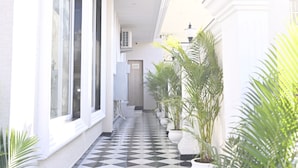 A corridor with a checkered floor, potted plants, and a door at the end. - Royal Residency Udaipur (Udaipur)