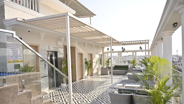 A rooftop terrace with outdoor seating, a patterned floor, and a view of the city. - Royal Residency Udaipur (Udaipur)