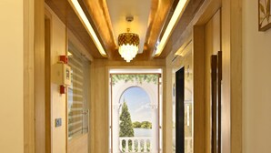A hallway with a wooden ceiling, a chandelier, and a view of the outdoors. - Royal Residency Udaipur (Udaipur)