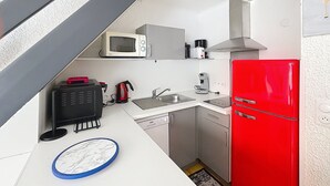 Eine kleine Küche mit Mikrowelle, Kaffeemaschine, Wasserkocher und einem roten Kühlschrank.