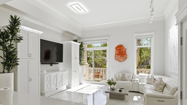 Una sala de estar moderna con un sofá blanco, un televisor de pantalla plana y un ventanal grande.