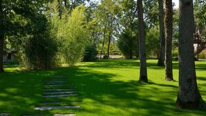 Un sendero que atraviesa una zona verde bordeada de árboles, con un edificio al fondo.