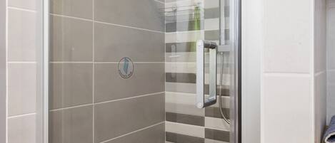 A shower with a glass door, a towel rack, and a logo on the wall.