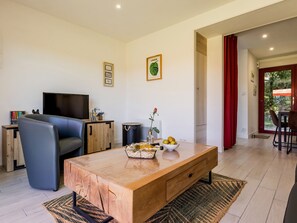 Un salon moderne avec une table basse en bois, un canapé, un téléviseur et un coin repas agrémenté de rideaux rouges.